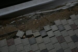 A homeowner observes damaged shingles, clogged gutters, and a ceiling water stain during a careful roof inspection.